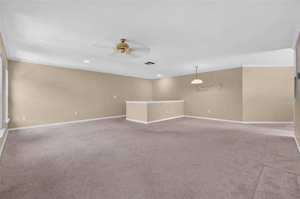 A spacious, carpeted room features a ceiling fan, a pendant light, and a half wall — 760 CENTERVALE DRIVE UNIT 201, CELEBRATION, FL
