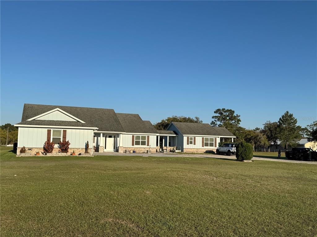 A light blue house with a stone base and a detached garage sits on grass — 4155 ALBRITTON ROAD, ST CLOUD, FL