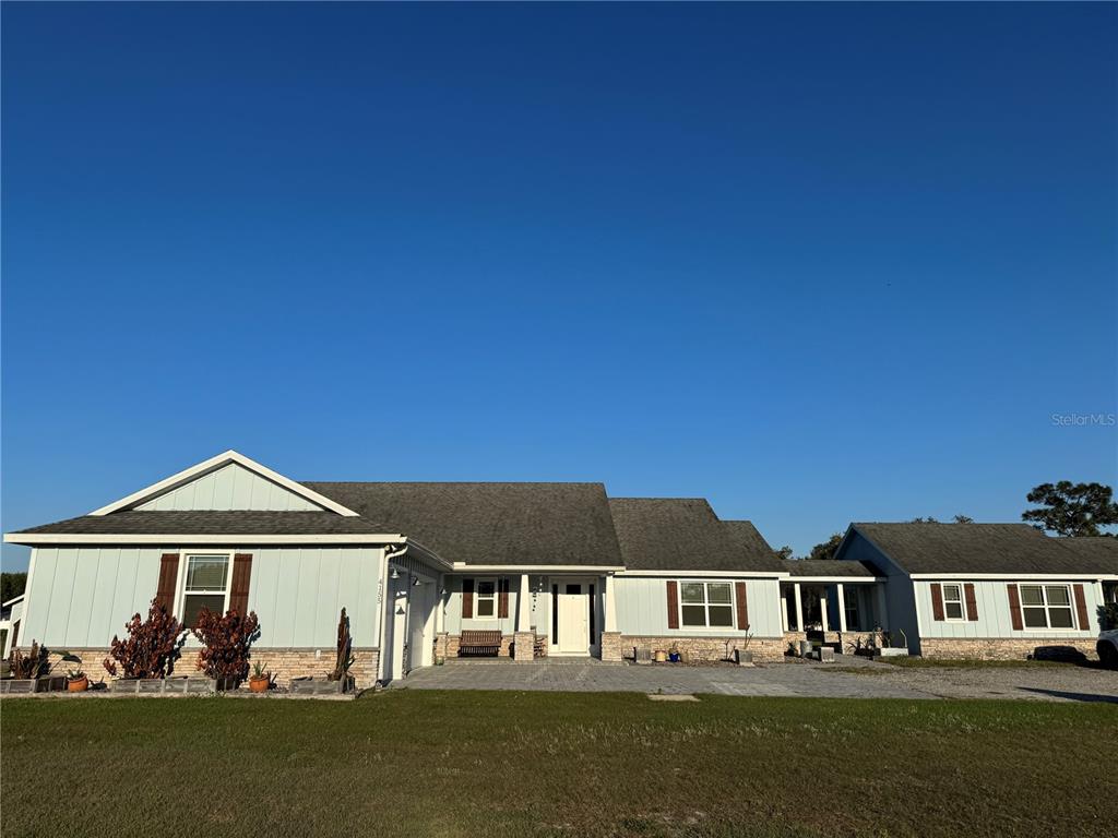 A single-story house with light blue siding, stone accents, and a gray shingled roof — 4155 ALBRITTON ROAD, ST CLOUD, FL