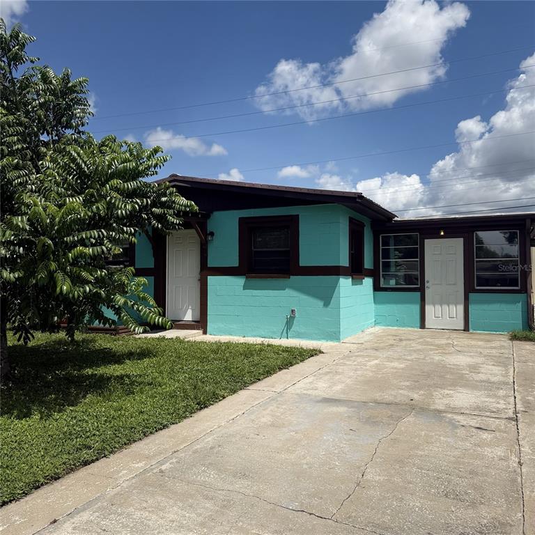 A turquoise, single-story house with two white doors and a concrete driveway under a blue sky — 2884 TROPIC RD, MELBOURNE, FL