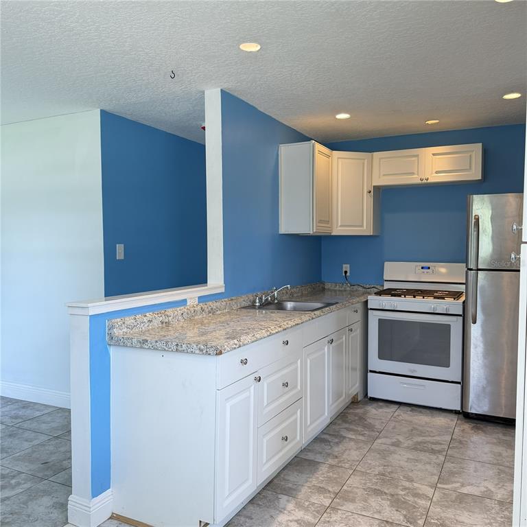 A kitchen features white cabinets, granite countertops, stainless steel appliances, and bright blue walls — 2884 TROPIC RD, MELBOURNE, FL