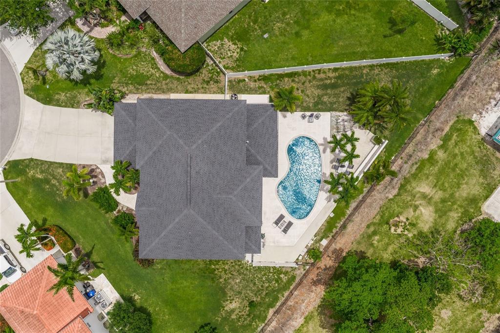 An aerial view shows a house with a dark shingled roof, pool, and surrounding lawn — 9214 18TH DRIVE NW, BRADENTON, FL