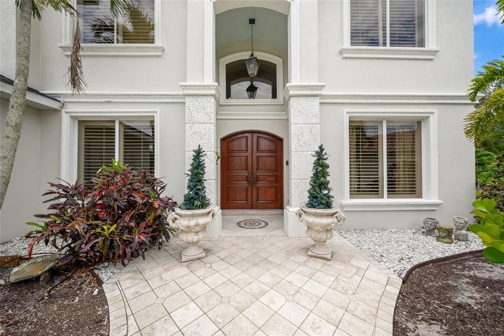 A two-story house exterior features a wooden double door entrance with two large stone planters — 9214 18TH DRIVE NW, BRADENTON, FL
