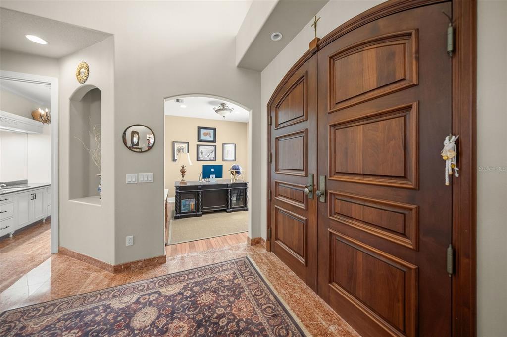 An entryway features double wood doors, marble flooring, an area rug, and an arched doorway — 9214 18TH DRIVE NW, BRADENTON, FL