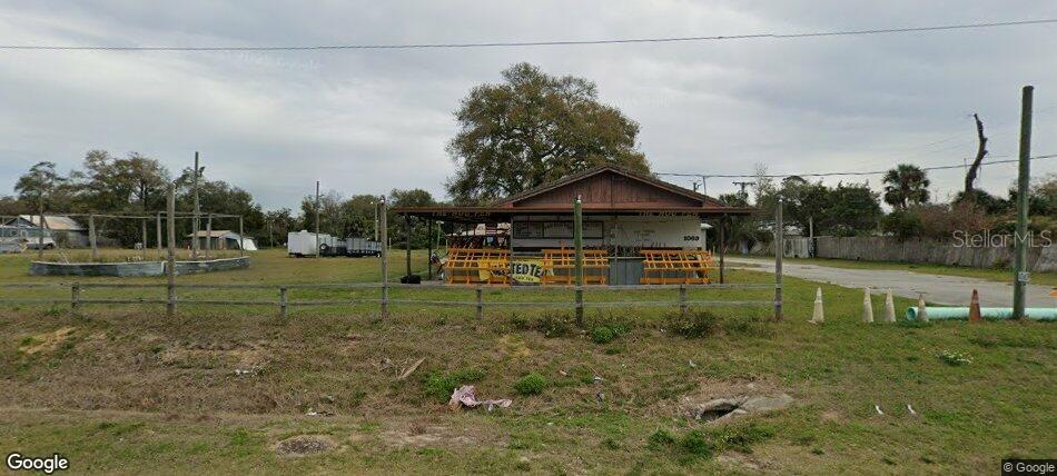 A single-story building with a covered porch sits on a grassy lot with a fence — 1069 N US HIGHWAY 1, ORMOND BEACH, FL