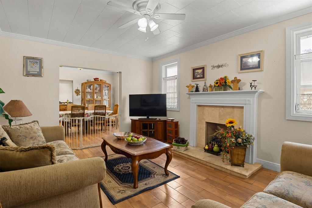 A living room features wood-look flooring, two beige sofas, a coffee table, and a ceiling fan — 207 S PERRY AVENUE, FORT MEADE, FL
