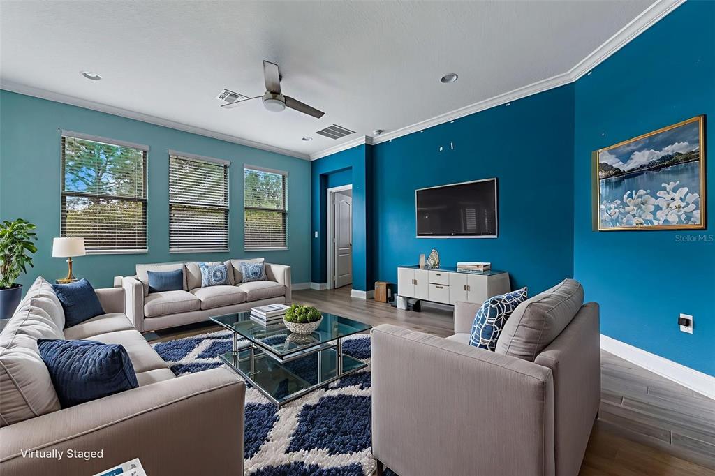 A living room features light gray sofas, a glass coffee table, and blue accent walls — 281 ANCONA AVENUE, DEBARY, FL