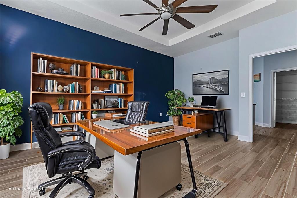 A home office features a dark blue accent wall, wooden bookshelves, and a wood-topped desk — 281 ANCONA AVENUE, DEBARY, FL