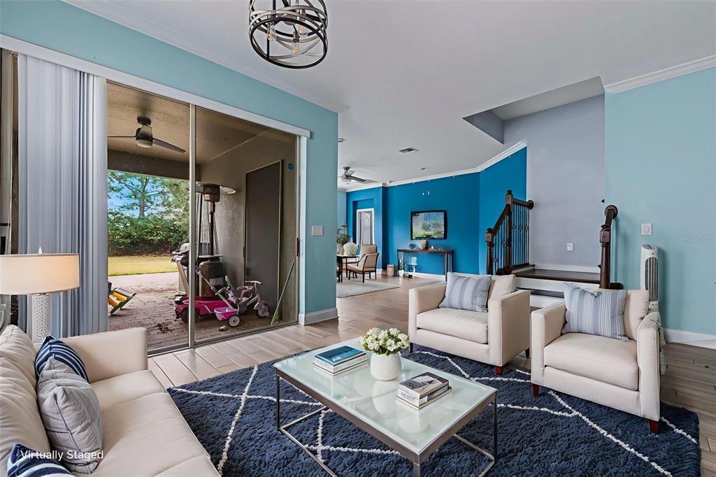A living room with light blue walls, a dark blue rug, and a sliding glass door — 281 ANCONA AVENUE, DEBARY, FL