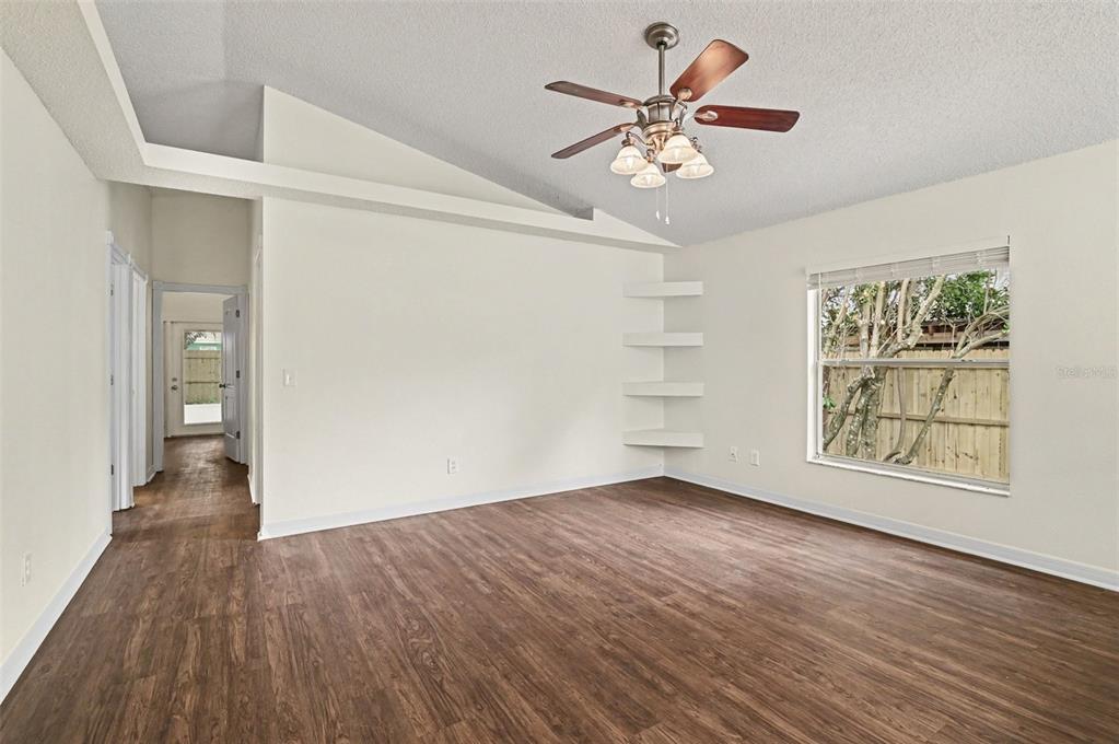 A room with wood-look flooring, a vaulted ceiling, a ceiling fan, and built-in wall shelves — 317 MCCOY VILLAGE COURT, APOPKA, FL