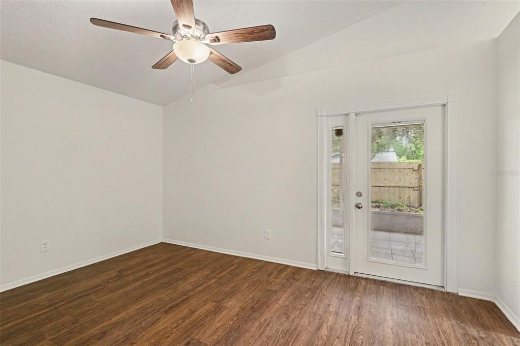An empty room with wood-look flooring, a ceiling fan, and a glass door to a patio — 317 MCCOY VILLAGE COURT, APOPKA, FL