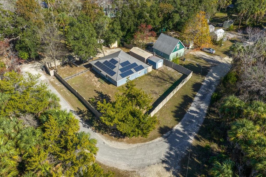 An aerial view shows a house with solar panels, a fenced yard, and surrounding trees — 12575 W FOSS GROVES PATH, INGLIS, FL