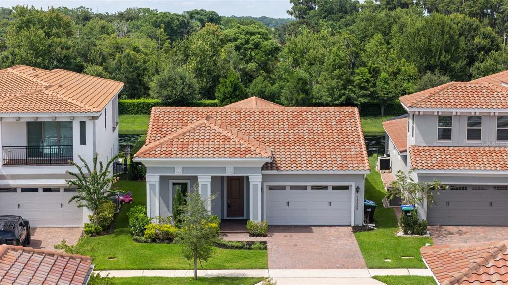 An aerial view shows a single-story house with a tiled roof between two taller homes — 13355 BROMBOROUGH DRIVE, ORLANDO, FL