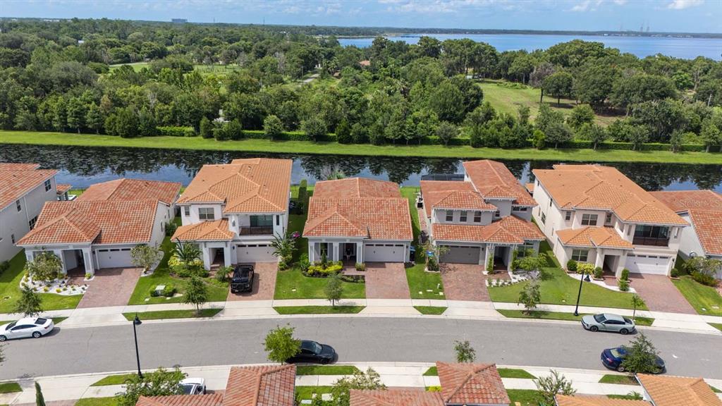 An aerial view shows a row of suburban houses with tile roofs facing a canal — 13355 BROMBOROUGH DRIVE, ORLANDO, FL