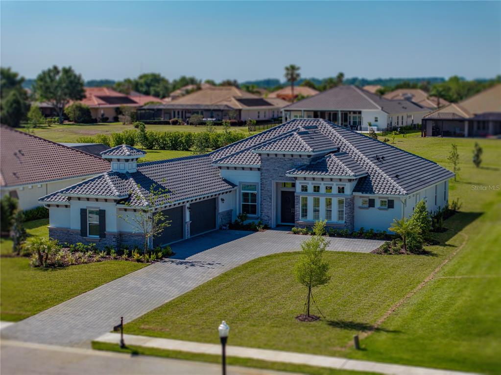 An aerial view of a single-story house with a tiled roof and stone facade — 13805 CARRYBACK DRIVE, DADE CITY, FL