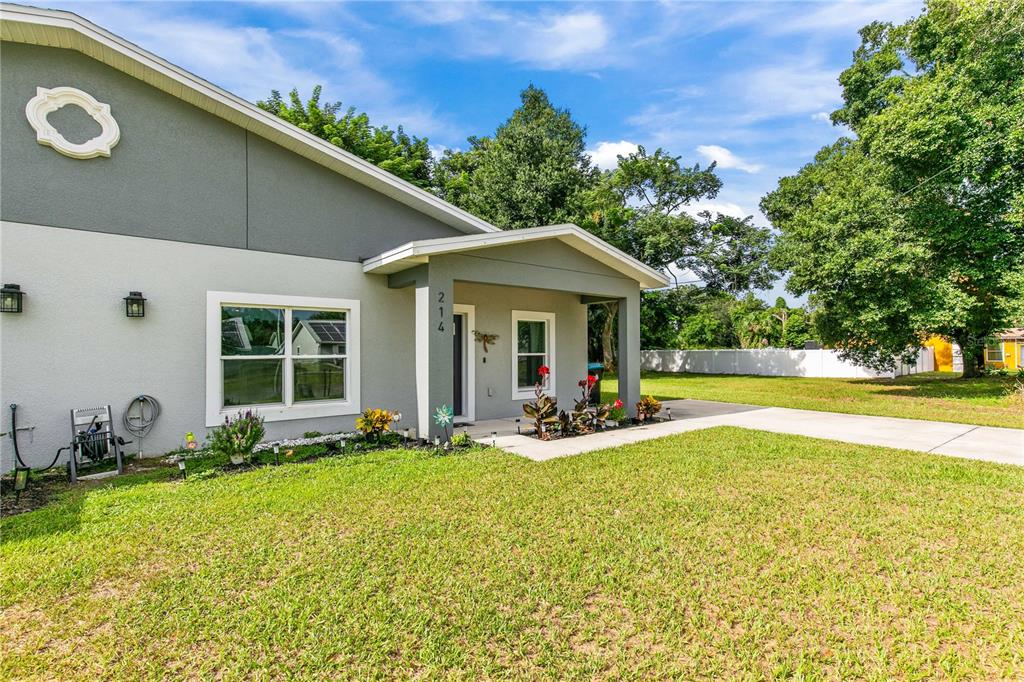 A gray house exterior features a covered entryway, a front lawn, and a concrete driveway — 214 W 15TH STREET, APOPKA, FL