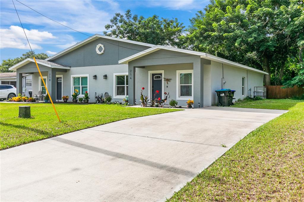 A gray duplex with two front entrances, concrete driveways, and a grassy front yard — 214 W 15TH STREET, APOPKA, FL