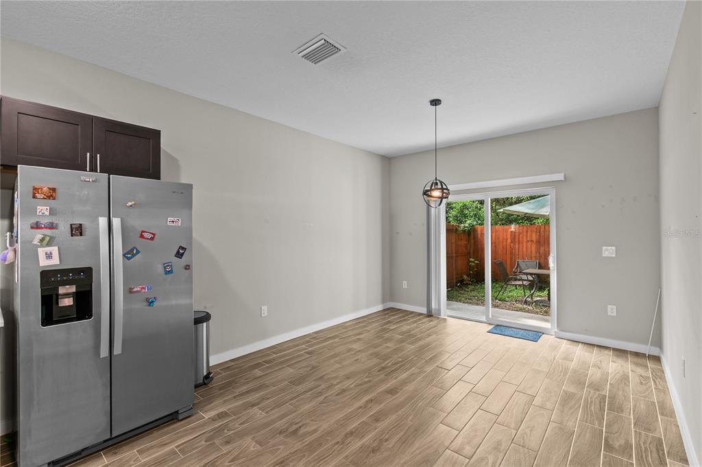 An open-concept living and dining area features tile flooring, a brown sectional, and dark cabinetry — 214 W 15TH STREET, APOPKA, FL
