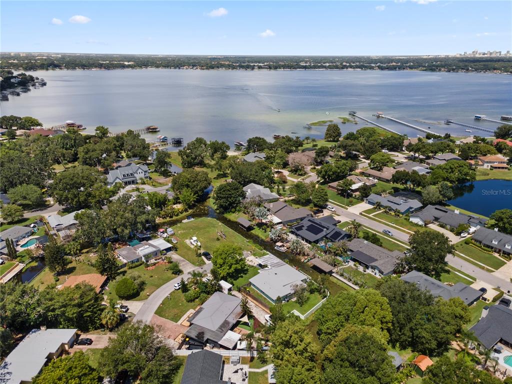 An aerial view shows a residential neighborhood situated along a large lake with private docks — 6809 WILLOUGHBY LANE, BELLE ISLE, FL