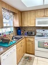 A kitchen features light wood cabinets, granite countertops, a white dishwasher, and a white stove — 1656 S LAKE AVENUE UNIT 3, CLEARWATER, FL