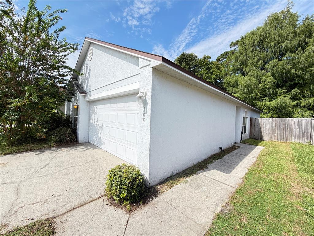 A white stucco house features a two-car garage, a concrete driveway, and a side walkway — 108 KAWILLA COURT, ORLANDO, FL