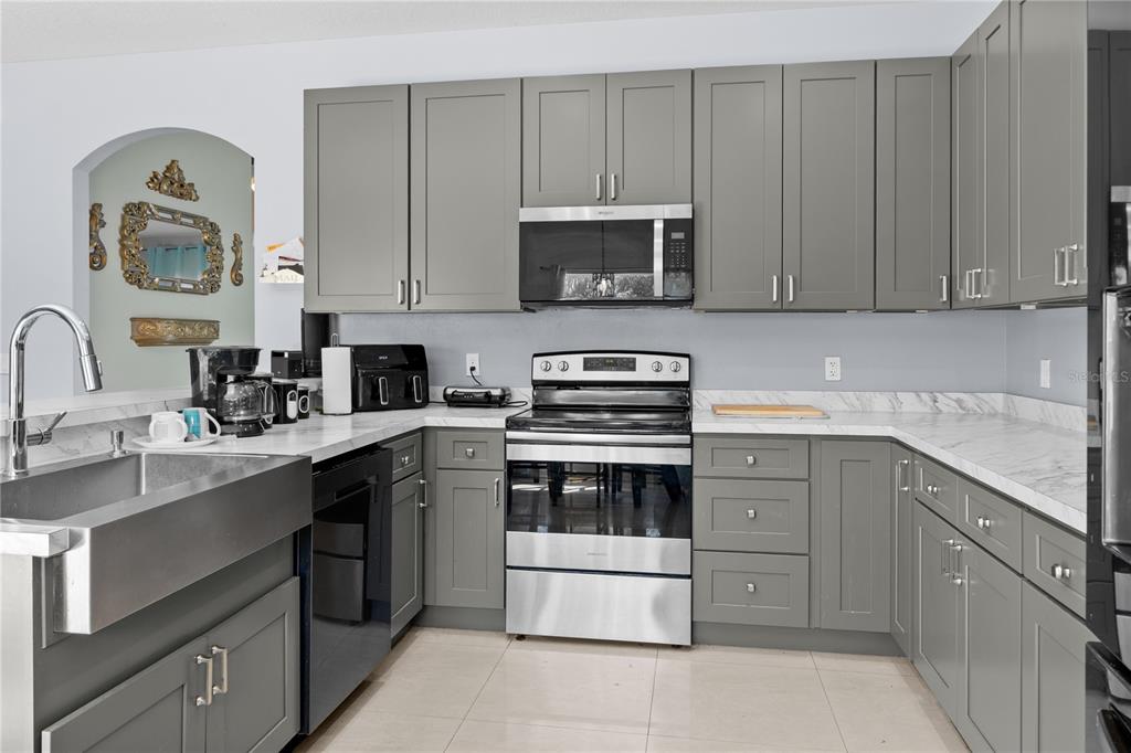 A kitchen features gray shaker cabinets, stainless steel appliances, and white marble-look countertops — 3663 DAYDREAM PLACE, ST CLOUD, FL