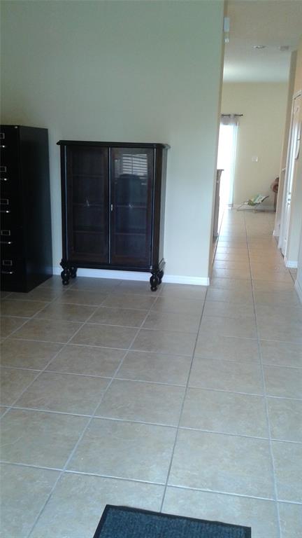 A tiled hallway leads past a dark wood cabinet toward a bright living area — 10725 SAVANNAH LANDING CIRCLE, ORLANDO, FL