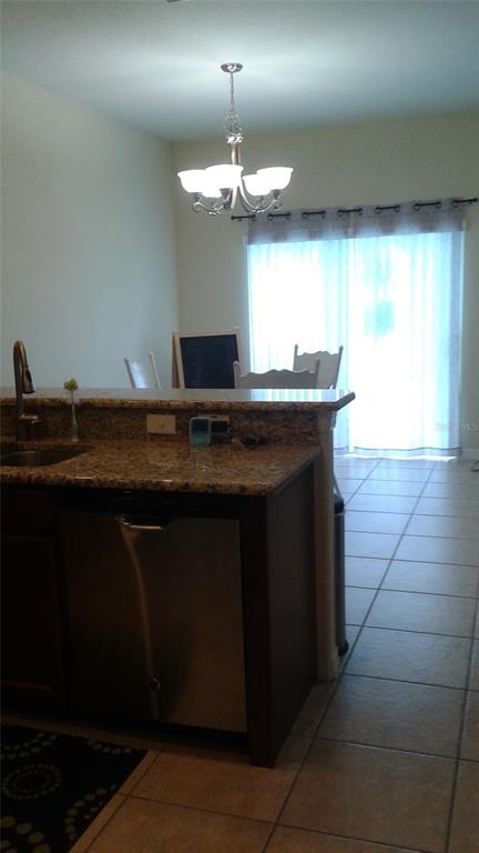 A kitchen island with a stainless steel dishwasher faces a dining area with a chandelier — 10725 SAVANNAH LANDING CIRCLE, ORLANDO, FL
