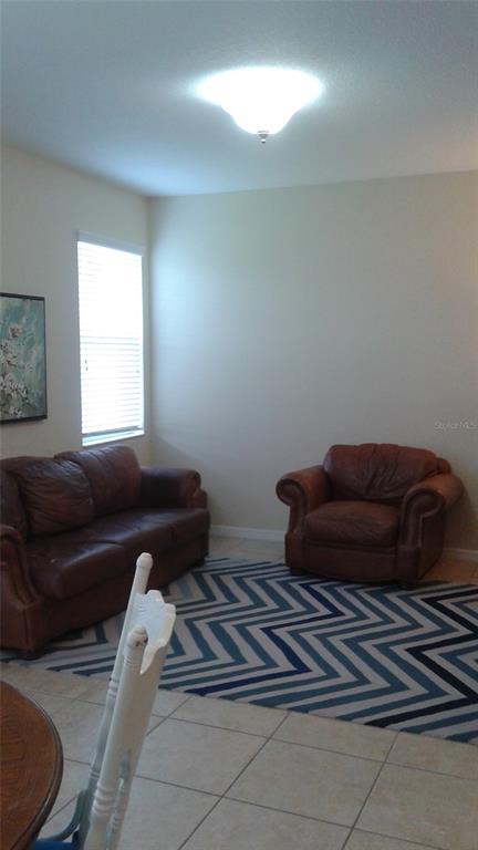 A living room features a brown leather sofa and armchair on a blue chevron rug — 10725 SAVANNAH LANDING CIRCLE, ORLANDO, FL