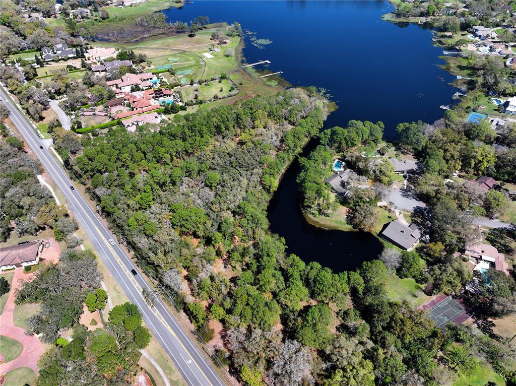 An aerial view shows a wooded lot situated between a road and a lake — MARKHAM WOODS ROAD, LONGWOOD, FL