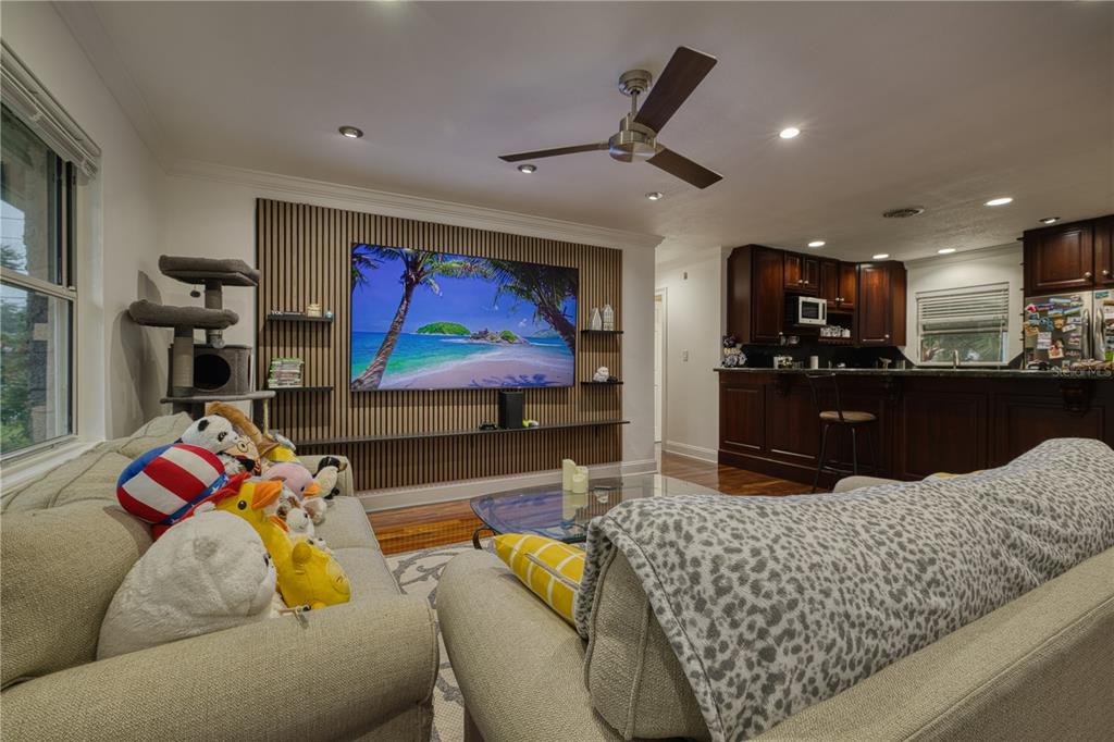 A living room features a slatted wood accent wall with a mounted television and plush seating — 5331 OAK COURT, WINTER PARK, FL