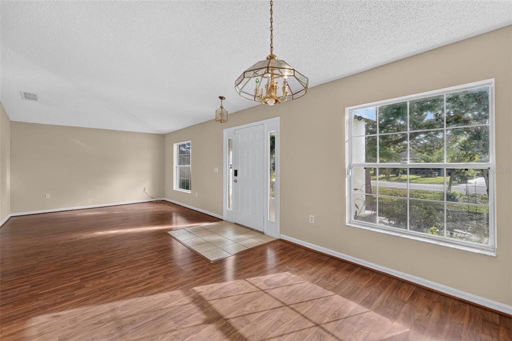 An entryway with wood flooring, a tiled landing, a white front door, and a chandelier — 1817 HUDSON DRIVE, POINCIANA, FL