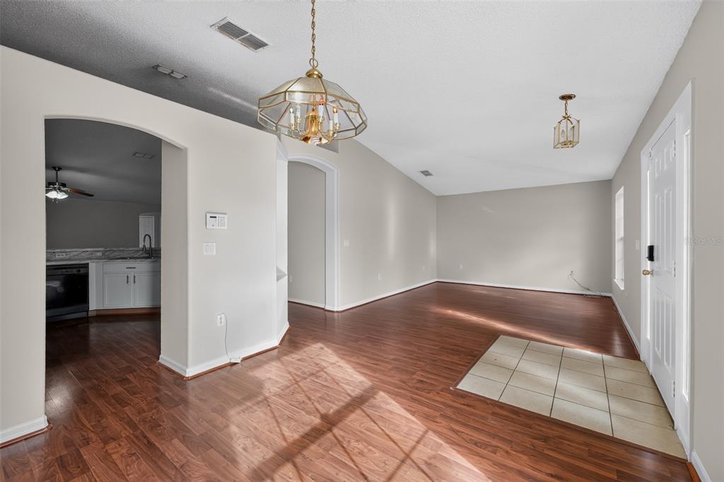 An open-concept living area features wood-look flooring, a tiled entryway, and a hanging light fixture — 1817 HUDSON DRIVE, POINCIANA, FL
