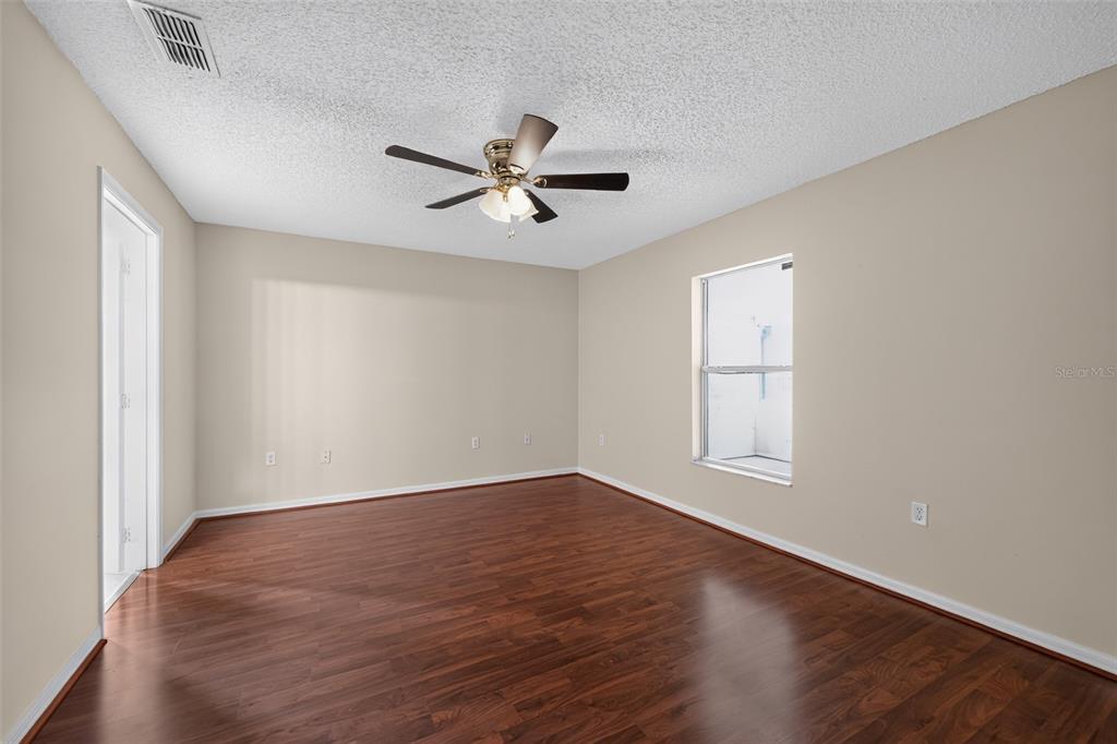 An empty bedroom with wood-look flooring, a ceiling fan, and a single window — 1817 HUDSON DRIVE, POINCIANA, FL