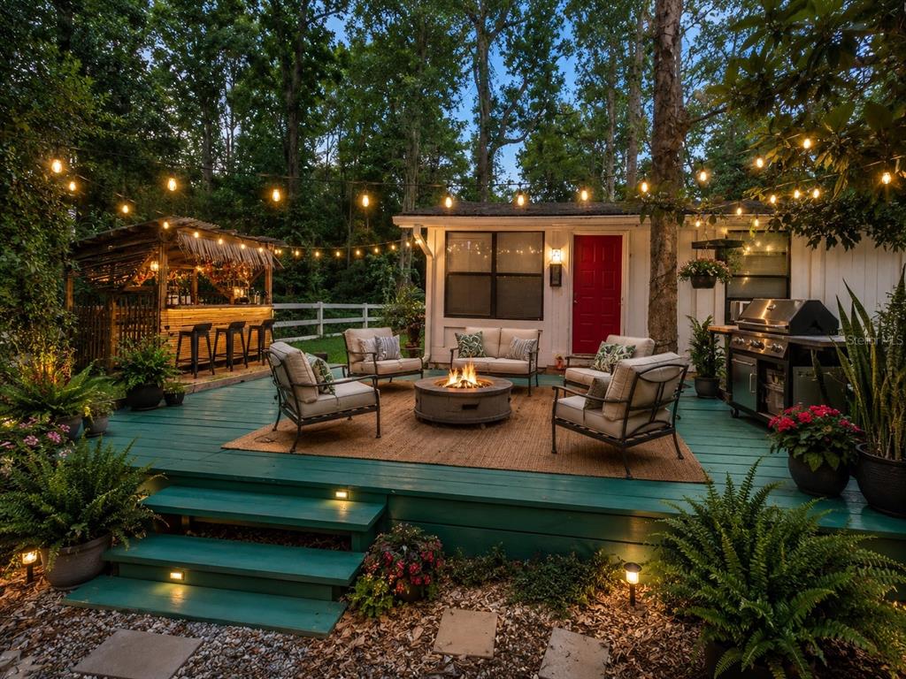 A backyard deck features a fire pit, outdoor seating, a tiki bar, and string lights — 1735 TIMOCUAN WAY, LONGWOOD, FL