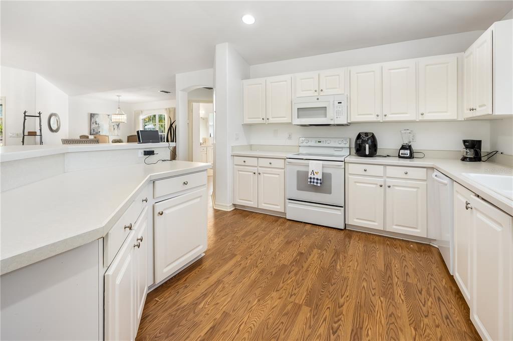 A kitchen features white cabinets, white appliances, and wood-look flooring — 9 SHERRINGTON DRIVE, ORMOND BEACH, FL