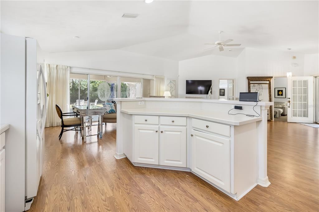 A kitchen island with white cabinets and a light countertop sits on wood-look flooring — 9 SHERRINGTON DRIVE, ORMOND BEACH, FL