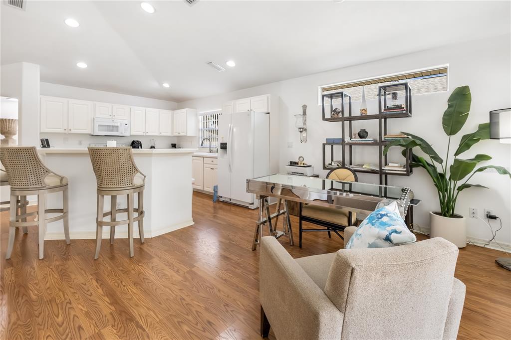 A kitchen with white cabinetry and a breakfast bar opens into a living area — 9 SHERRINGTON DRIVE, ORMOND BEACH, FL