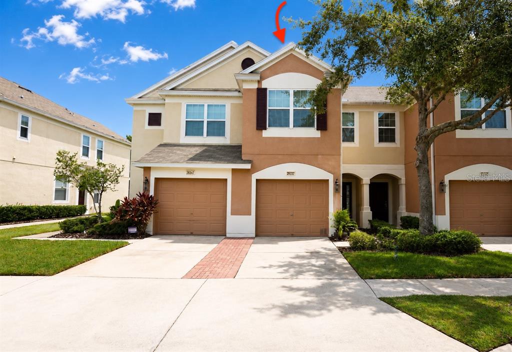 A two-story townhouse with two garage doors and a concrete driveway — 26543 CASTLEVIEW WAY, WESLEY CHAPEL, FL