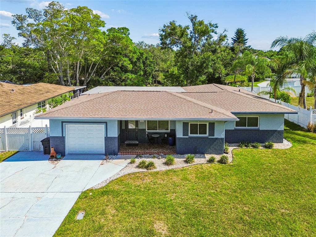 An exterior view of a single-story house with a two-tone facade and a concrete driveway — 3282 HONEYSUCKLE RD, LARGO, FL