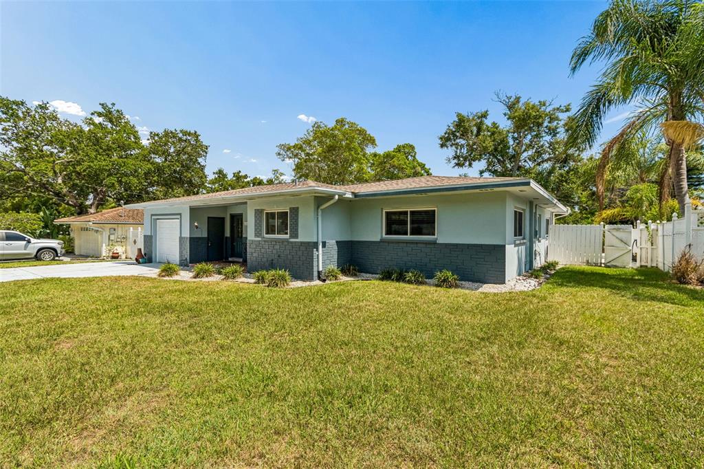 A single-story house with light blue siding, dark stone accents, and a front-facing garage — 3282 HONEYSUCKLE RD, LARGO, FL