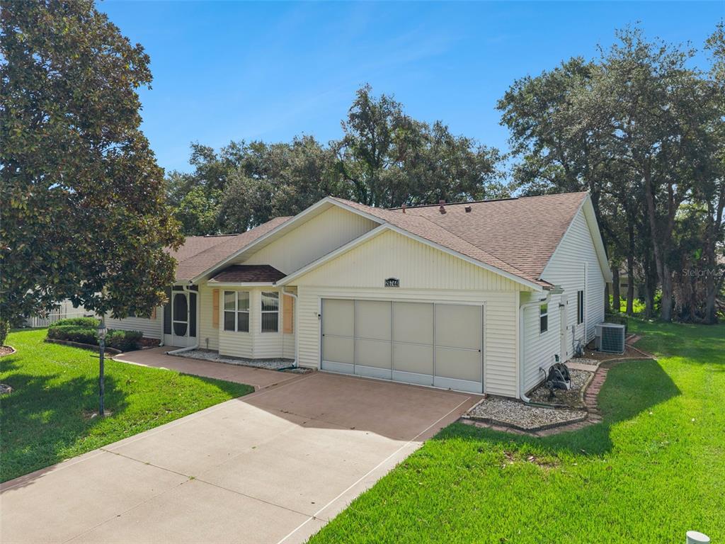 A single-story house with light-colored siding, a two-car garage, and a concrete driveway — 26744 RACQUET CIRCLE, LEESBURG, FL