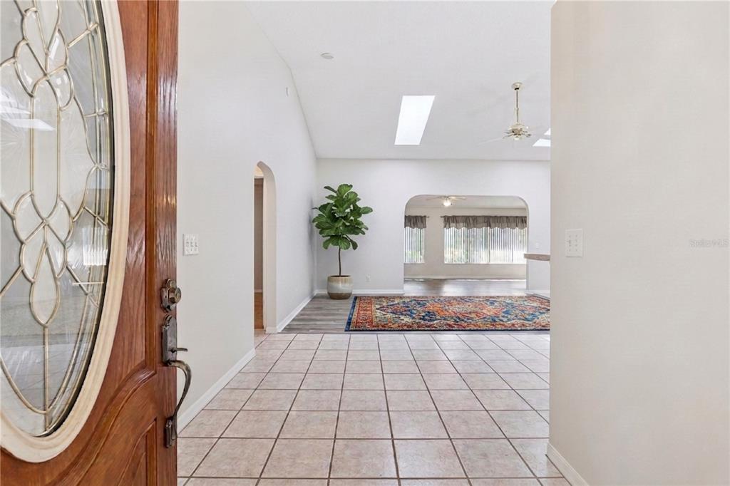 An entryway with tiled floors leads into a living area featuring a vaulted ceiling — 26744 RACQUET CIRCLE, LEESBURG, FL