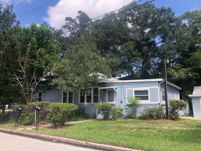 A light blue single-story house with a metal roof sits behind a grassy front yard — 106 E 12TH STREET, SANFORD, FL