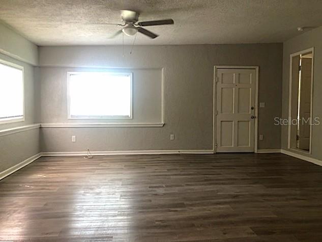 An empty room features gray walls, wood-look flooring, a ceiling fan, and a white door — 106 E 12TH STREET, SANFORD, FL