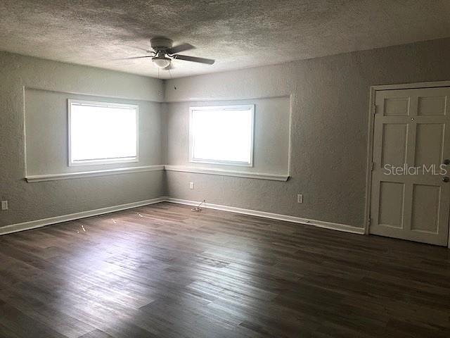 An empty room features gray walls, wood-look flooring, two windows, and a ceiling fan — 106 E 12TH STREET, SANFORD, FL