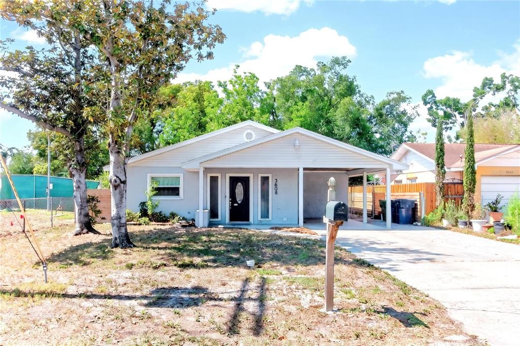 A single-story house with light gray siding, a black front door, and an attached carport — 3608 W CARMEN STREET, TAMPA, FL