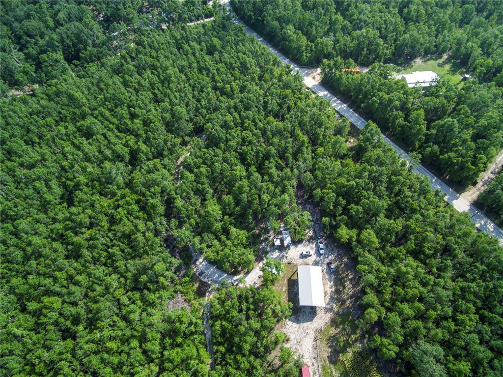 An aerial view shows a dense forest with a power line path and cleared land — 18233 185TH RD, LIVE OAK, FL