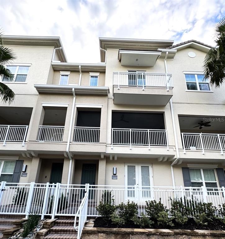 A multi-story townhouse exterior features balconies, a paved walkway, and parked cars in front — 1487 LAKE GEORGE DRIVE, LAKE MARY, FL