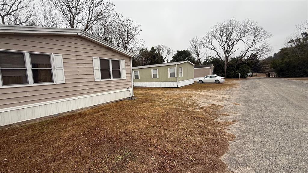 Two mobile homes sit on a gravel lot under a cloudy sky with bare trees — 12656 SE 78TH TERRACE, BELLEVIEW, FL